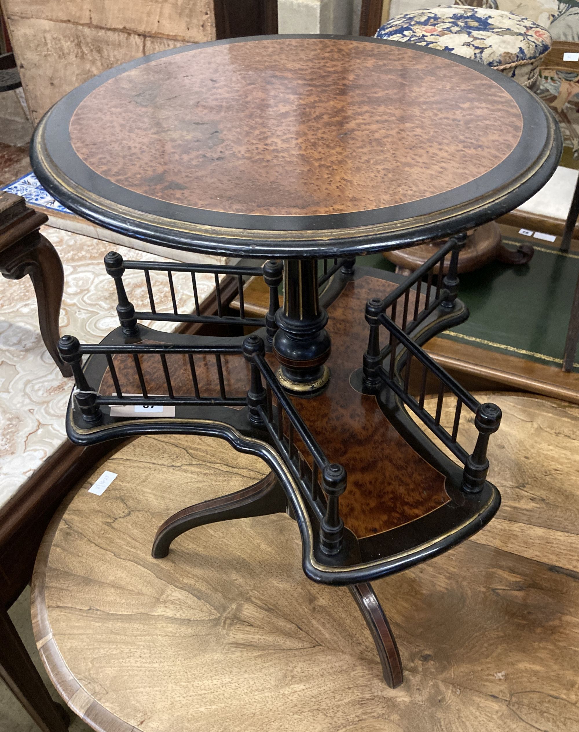 An ebonised and gilt thuya or walnut book table, the circular top over revolving trefoil book rack